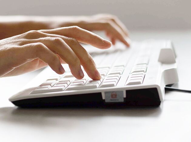 Hände die auf einer PC Tastatur tippen