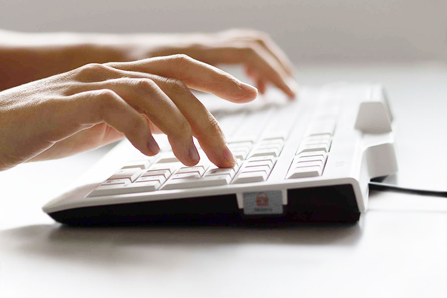 Hände die auf einer PC Tastatur tippen