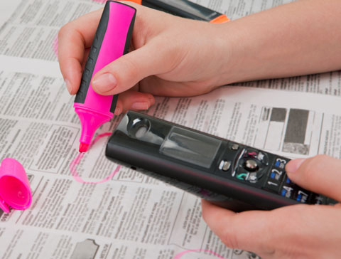 Anzeigenteil in einer Zeitung - Jobangebot wird per Textmarker markiert, Person hat Telefon in der Hand
